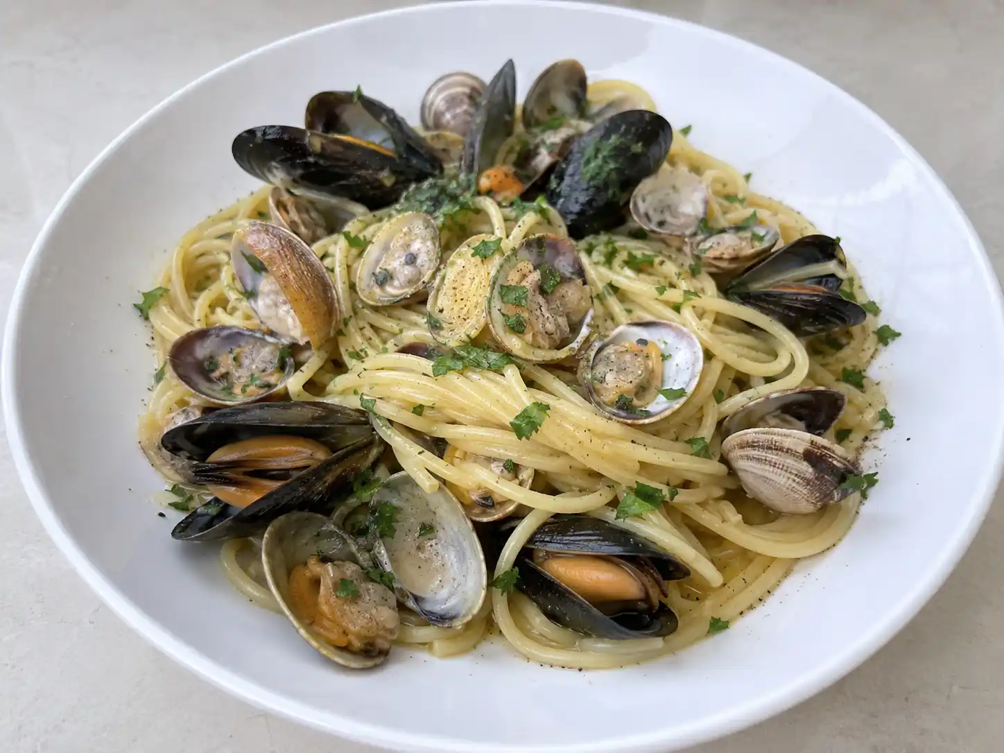 Cozze vongole pasta in bianco con spaghetti cremosi, gusci aperti e prezzemolo fresco