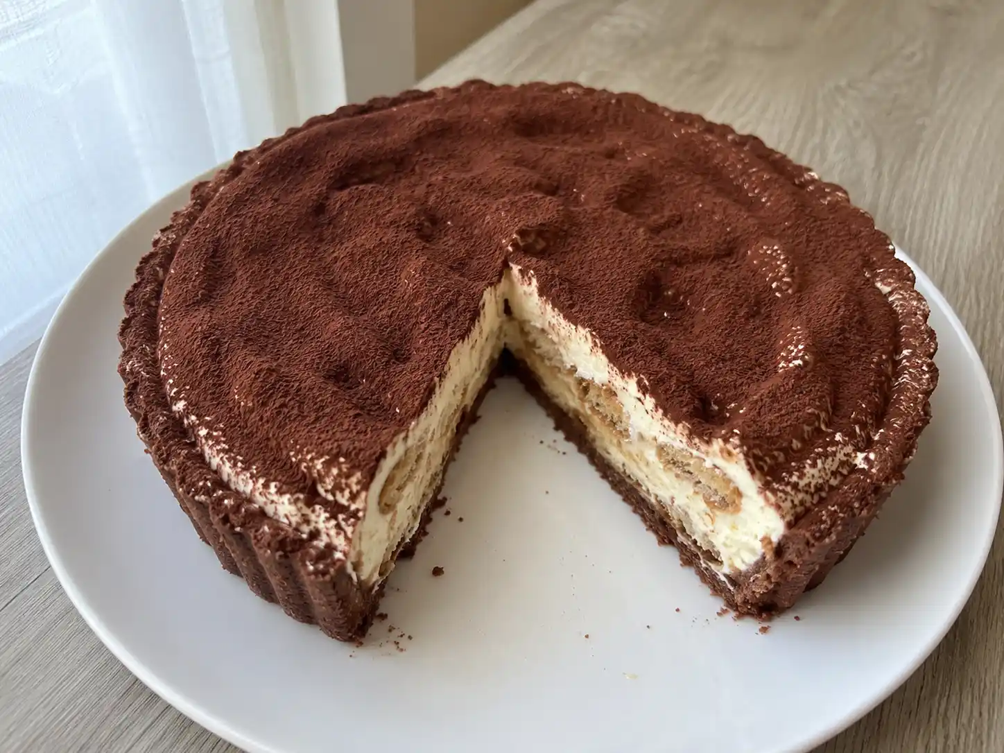 Crostata tiramisù con crema al mascarpone, cacao e savoiardi al caffè in un guscio al cacao