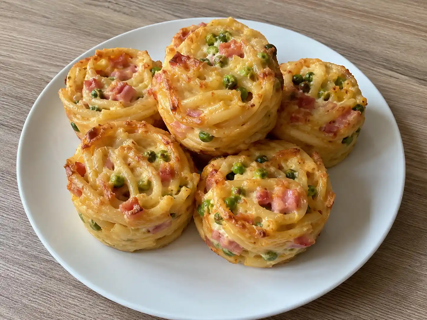 Frittatina di pasta al forno con bucatini dorati, scamorza filante, piselli e prosciutto cotto