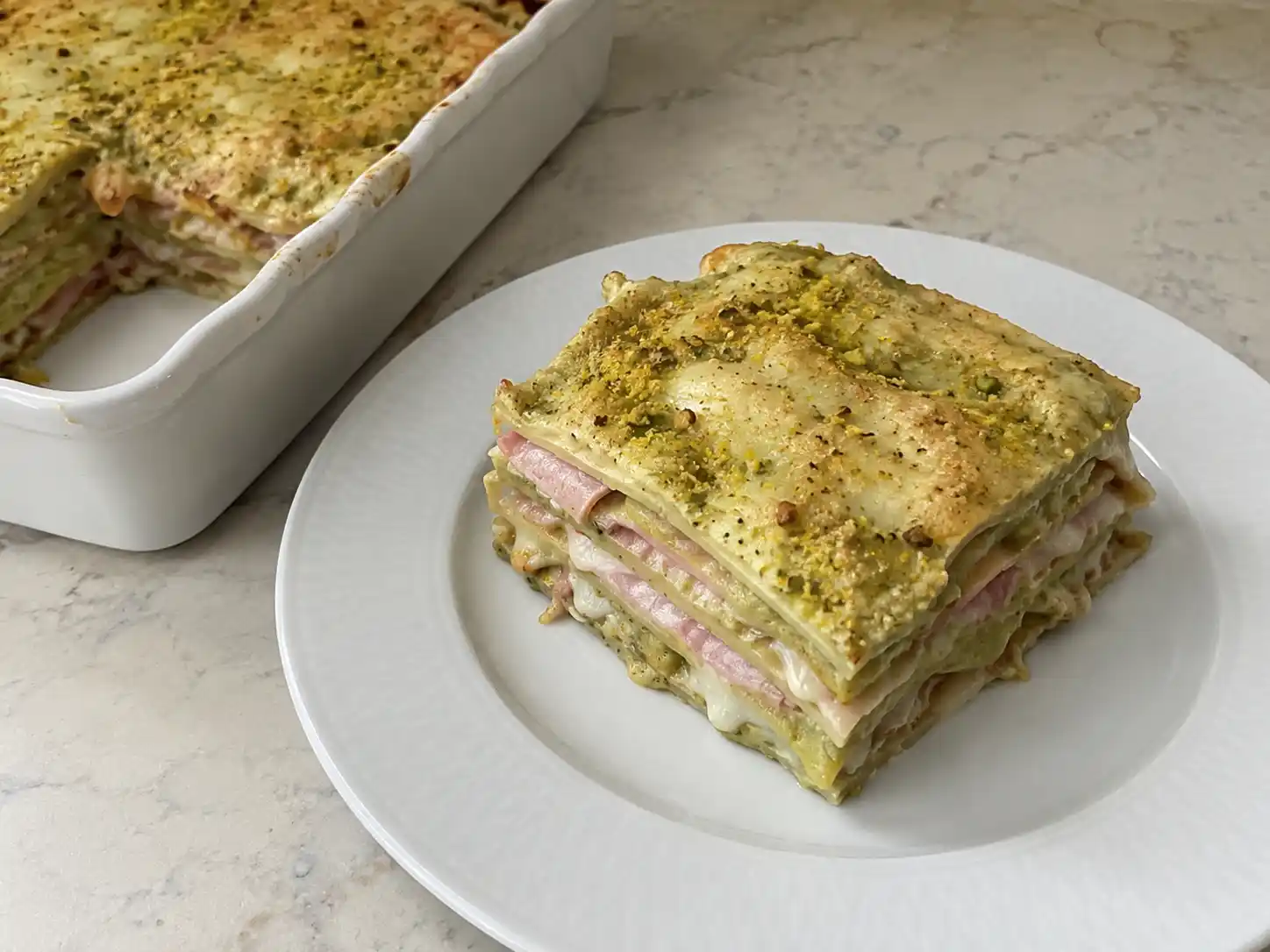 Lasagne al pistacchio a strati con mortadella, provola filante e superficie dorata in pirofila