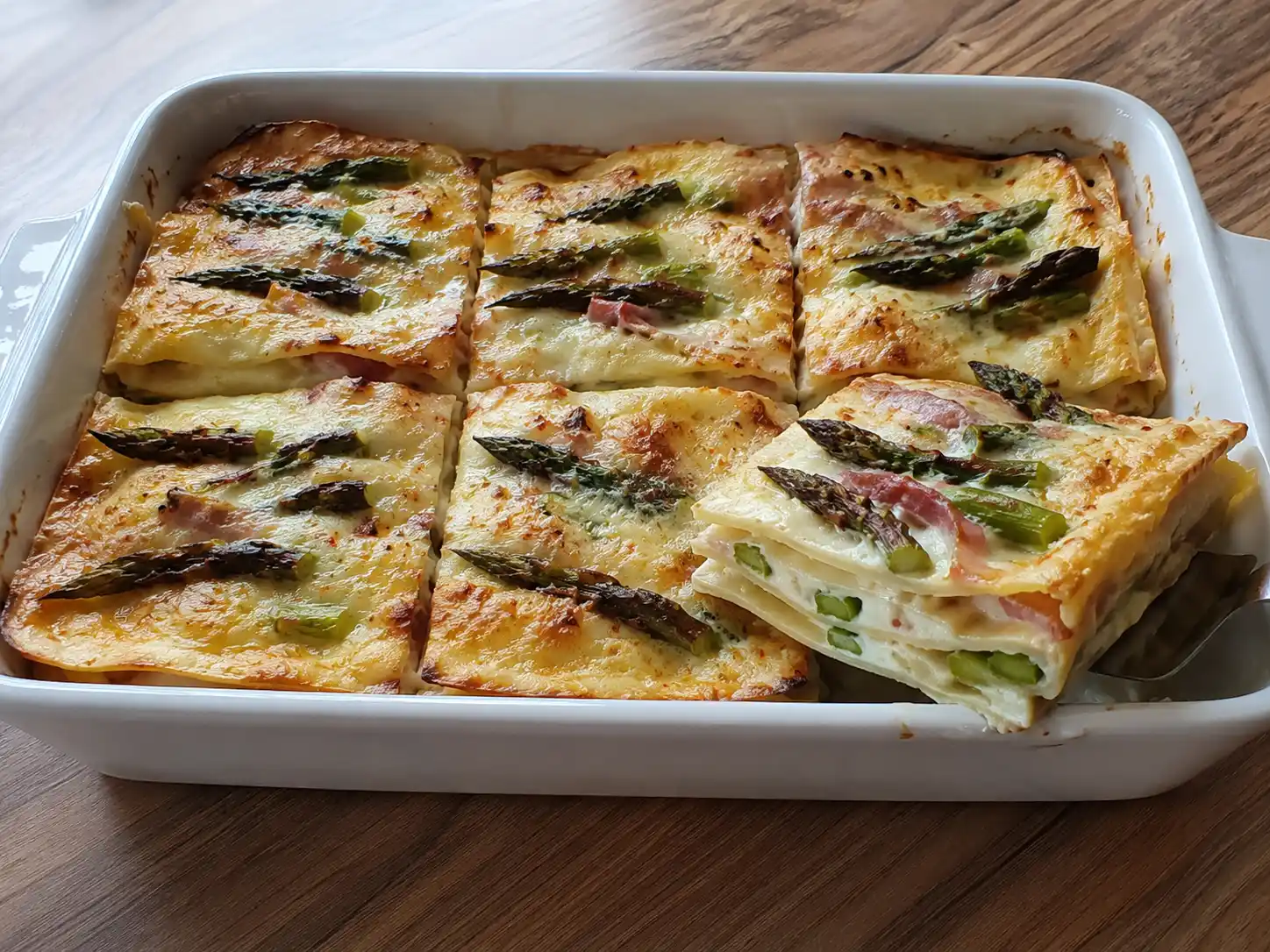 Lasagne con asparagi e speck cremose in teglia, con sfoglia dorata e punte verdi visibili