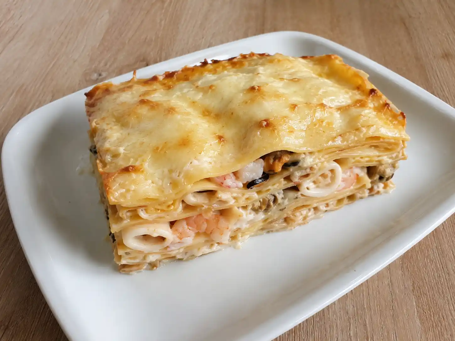 Lasagne di pesce al forno con besciamella, gamberi, calamari, cozze e vongole in teglia