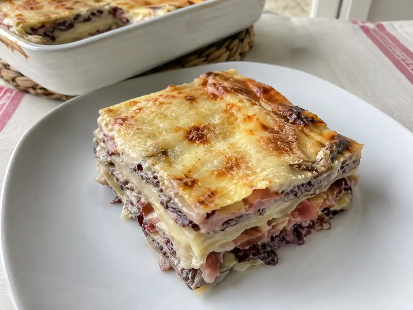 Lasagne radicchio e speck in porzione, cremose con besciamella e scamorza dorata in superficie