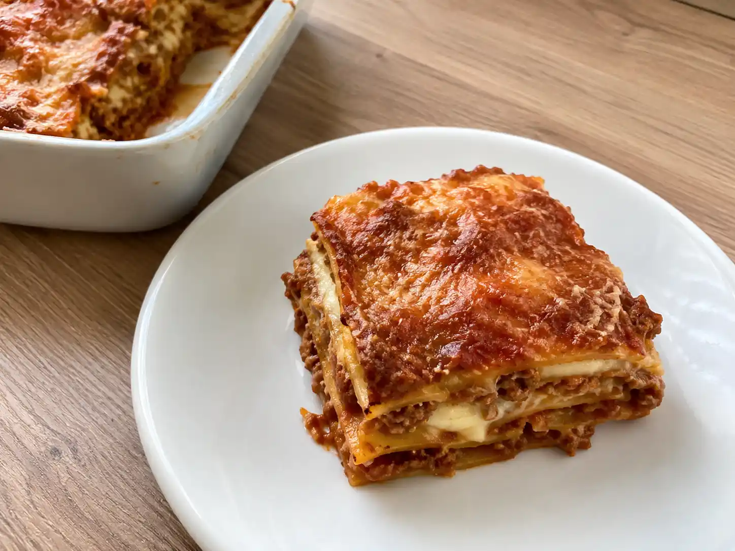 Lasagne senza besciamella al ragù con mozzarella filante e superficie dorata in teglia