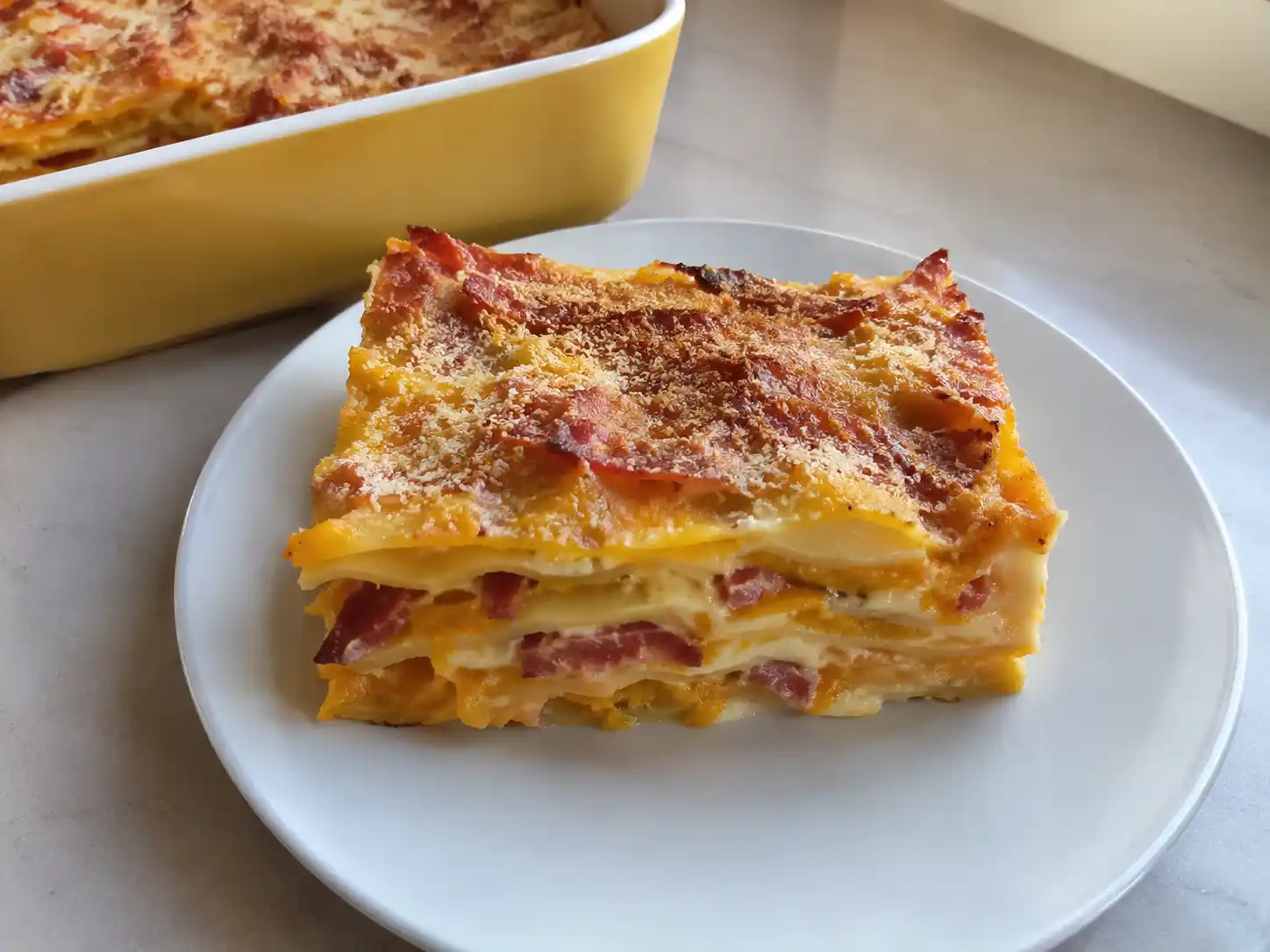 Lasagne zucca e speck in teglia con strati cremosi di besciamella e superficie dorata