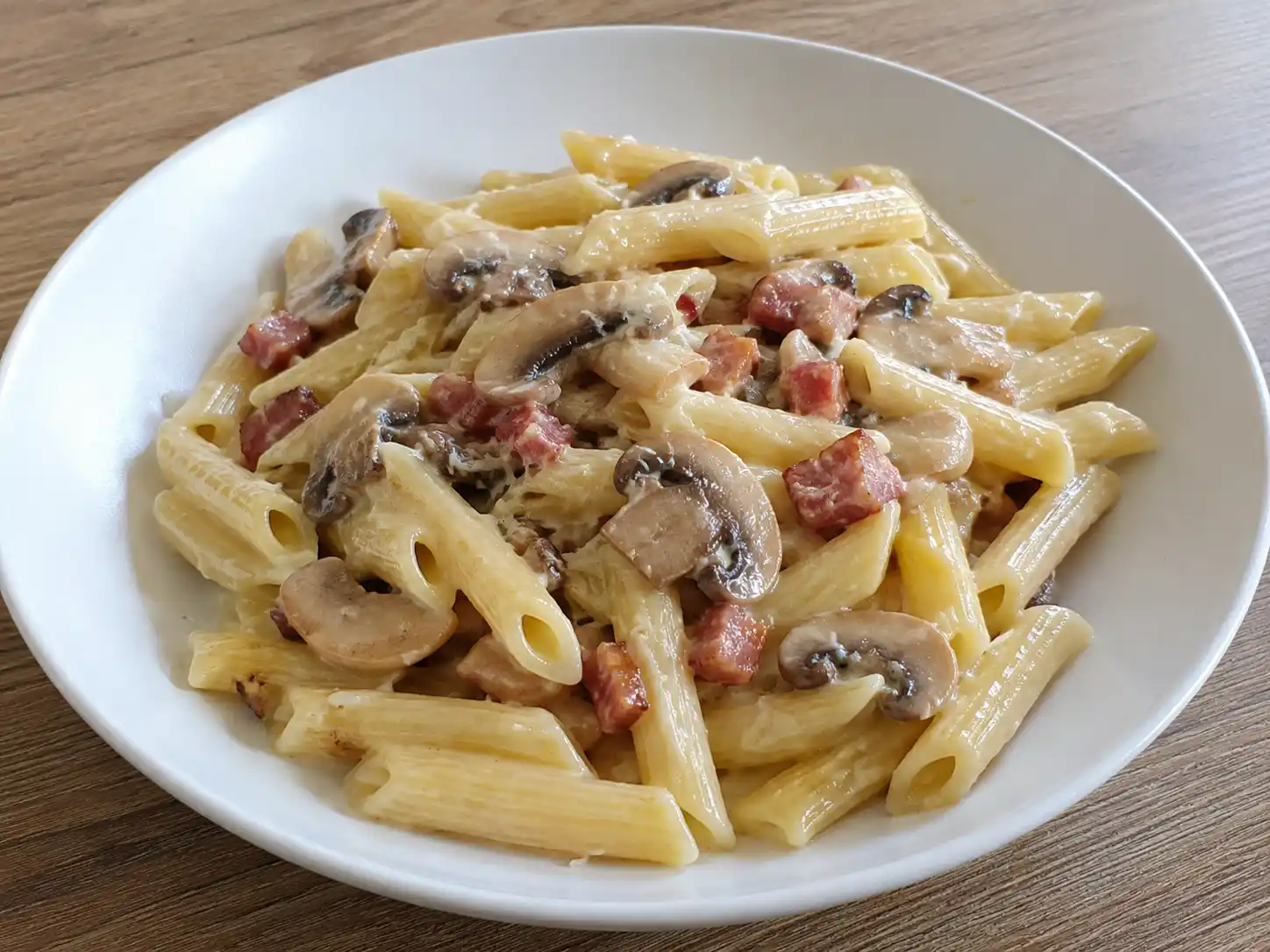 Pasta ai funghi e pancetta cremosa con panna, champignon rosolati e cubetti dorati