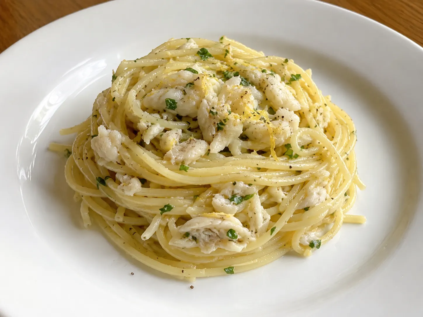 Pasta al baccalà in bianco con spaghetti lucidi, scaglie di pesce e prezzemolo fresco