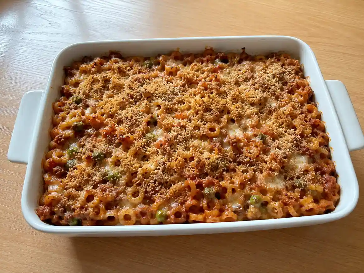 Pasta al forno con anelletti in teglia, con ragù, piselli, caciocavallo fuso e crosta dorata