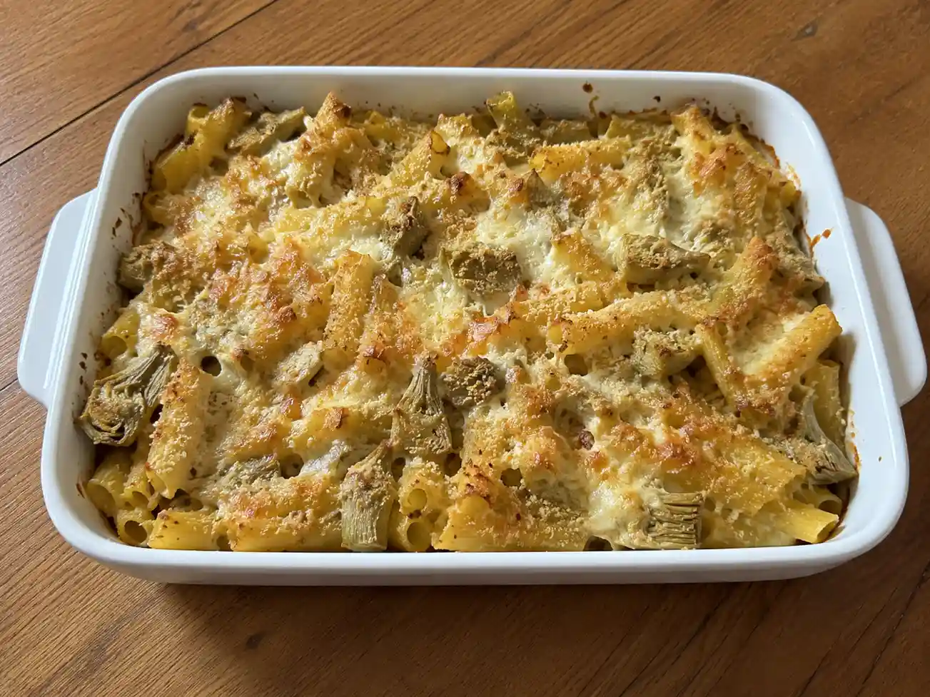 Pasta al forno con carciofi in teglia bianca, cremosa, con mozzarella e crosta dorata