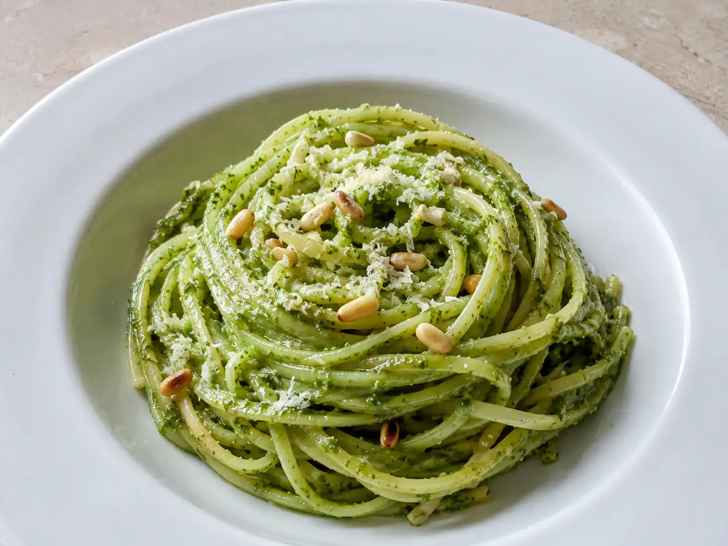 Pasta al pesto di rucola cremosa con linguine verdi, pinoli tostati e formaggio grattugiato