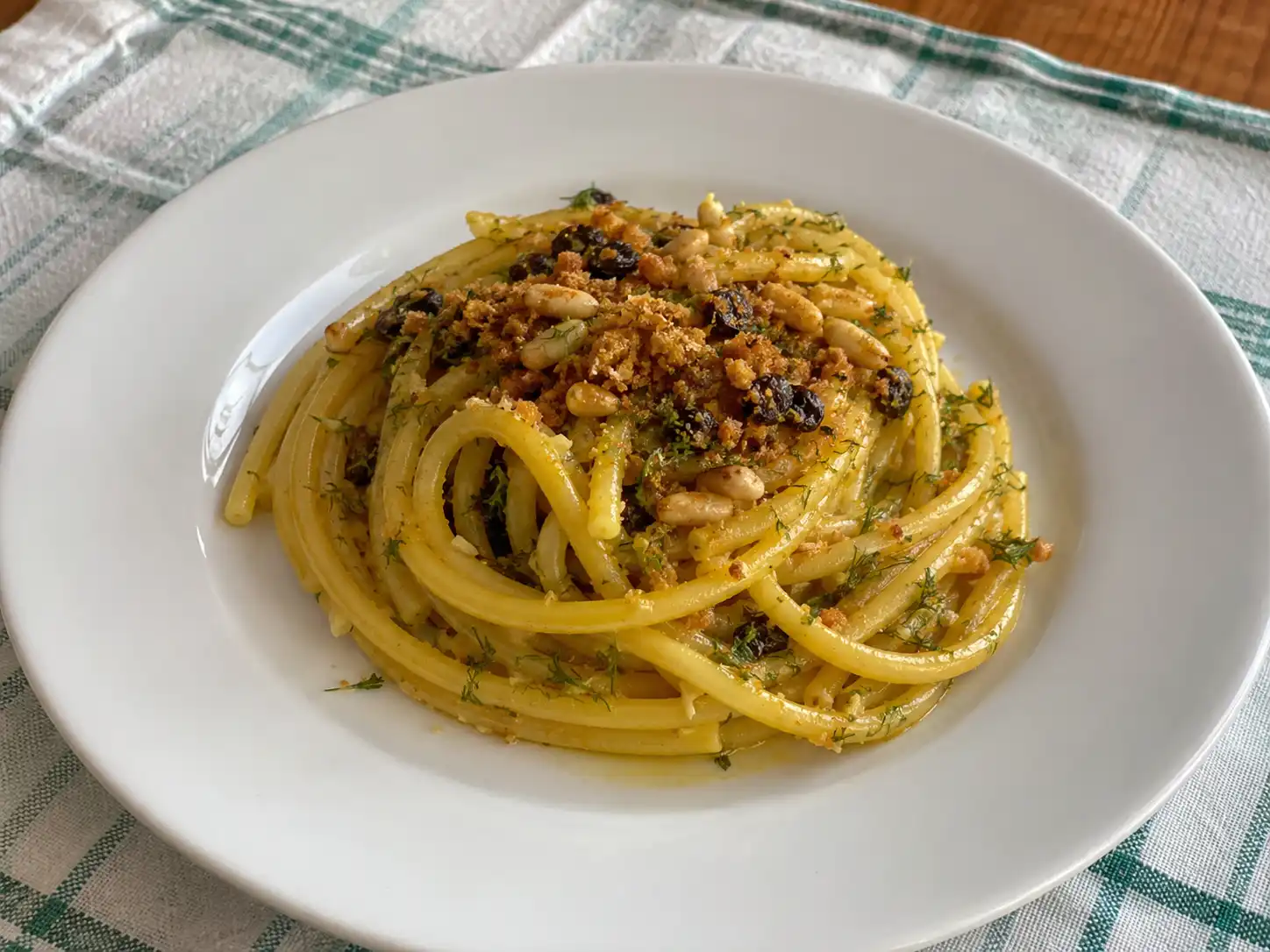 Pasta alla siciliana con acciughe in piatto bianco con finocchietto, pinoli, uvetta e pangrattato tostato