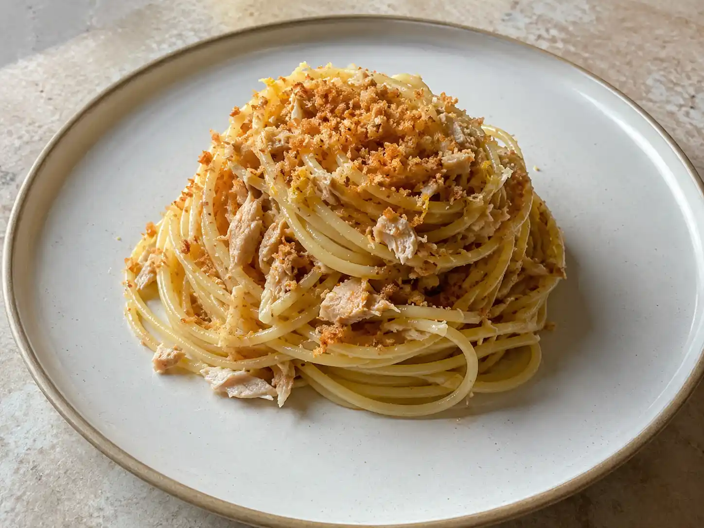 Pasta bottarga tonno in piatto chiaro con pangrattato tostato, limone grattugiato e spaghetti cremosi