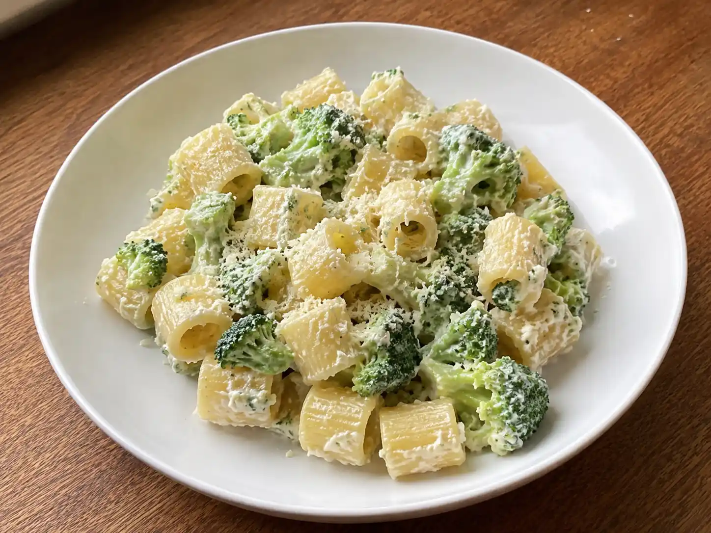 Pasta broccoli e ricotta cremosa con mezze maniche, cimette verdi e crema chiara nel piatto