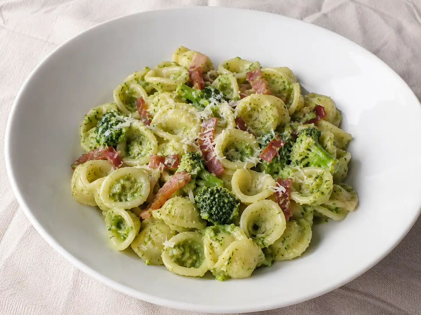 Pasta broccoli e speck cremosa con cimette verdi e speck croccante in piatto fondo
