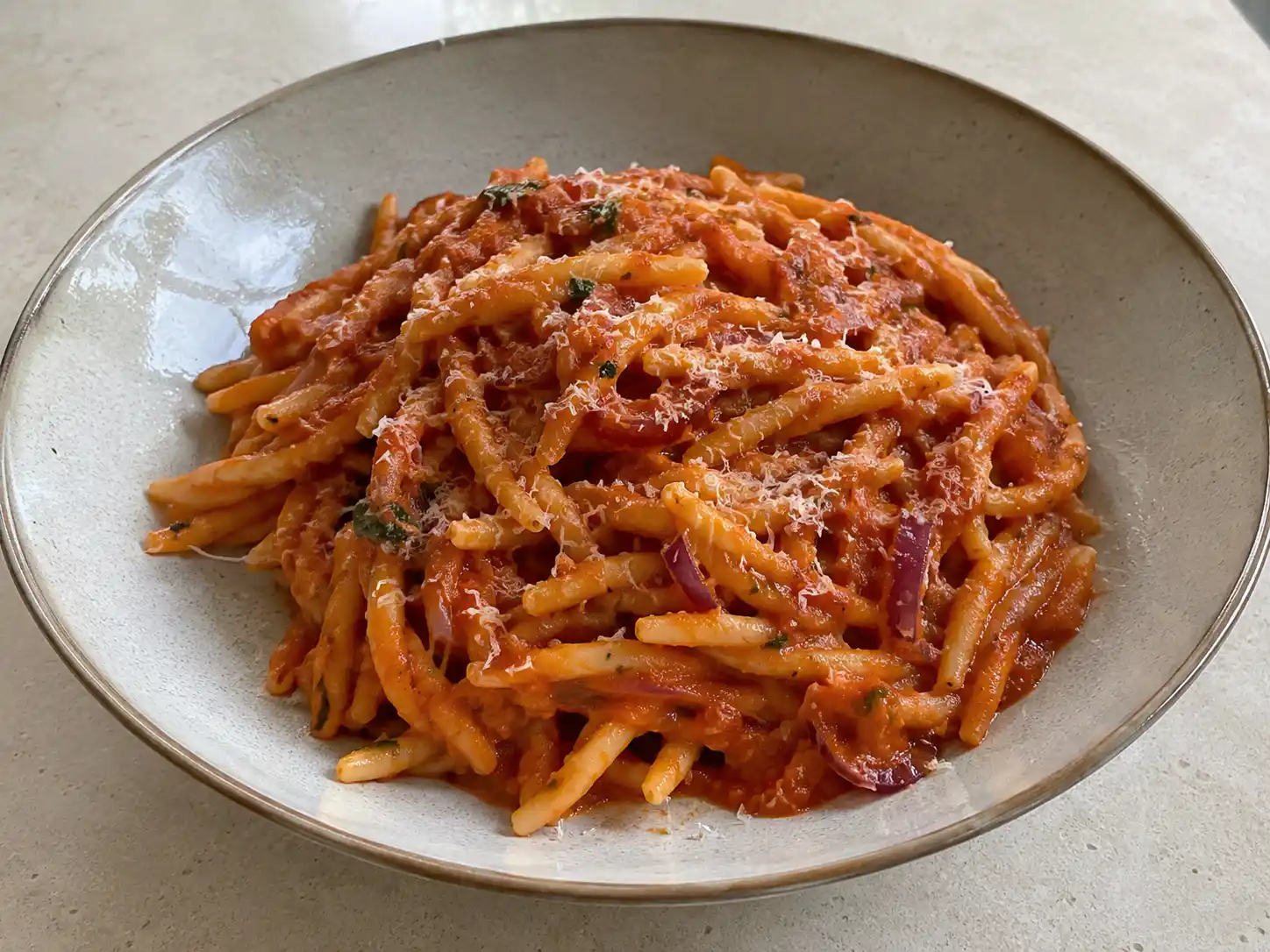 Pasta calabrese con ’nduja e cipolla rossa in sugo rosso cremoso, servita con fileja e pecorino