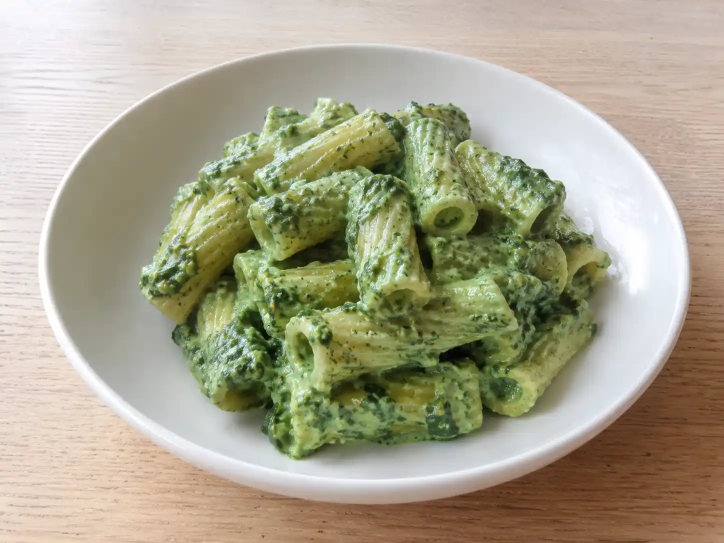 Pasta con crema di spinaci cremosa servita nel piatto con salsa verde di ricotta e Parmigiano