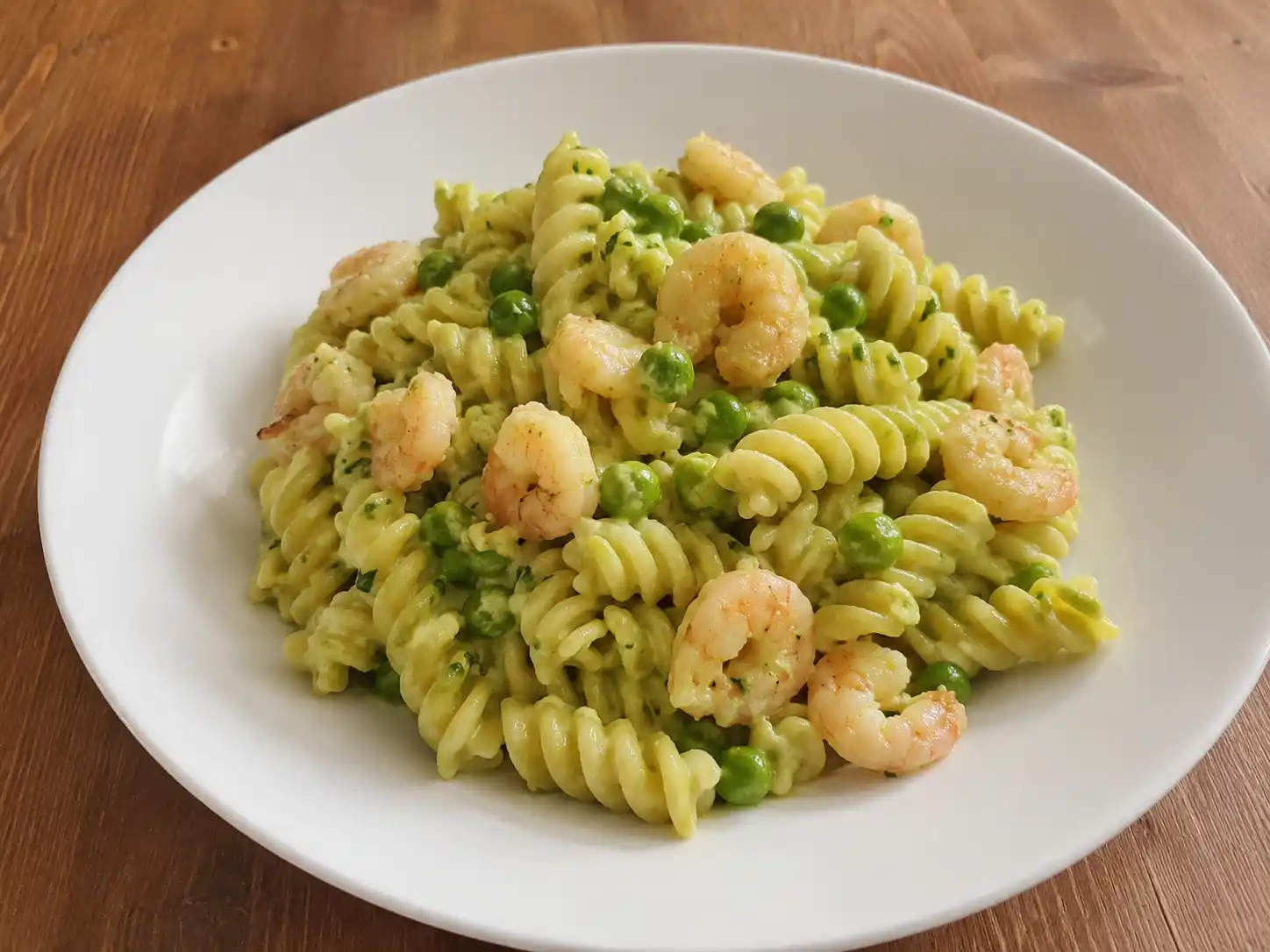Pasta con gamberetti e piselli cremosa con fusilli, piselli verdi e gamberetti in piatto chiaro