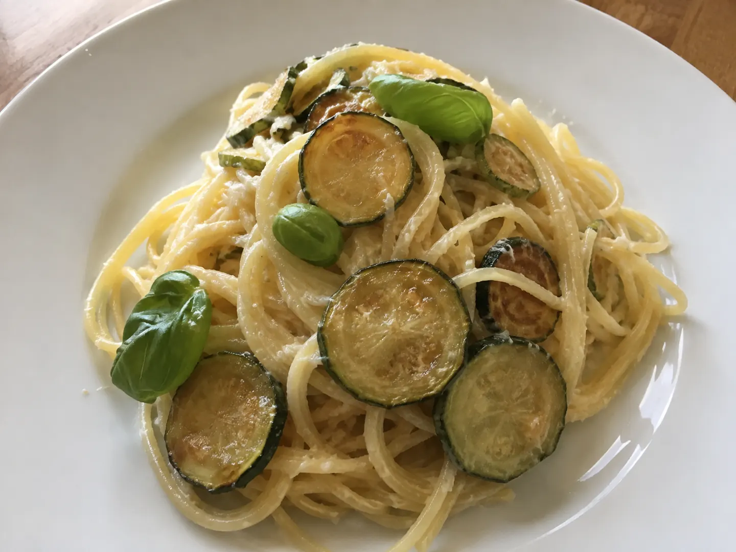 Pasta con le zucchine fritte cremosa con rondelle dorate e basilico fresco nel piatto