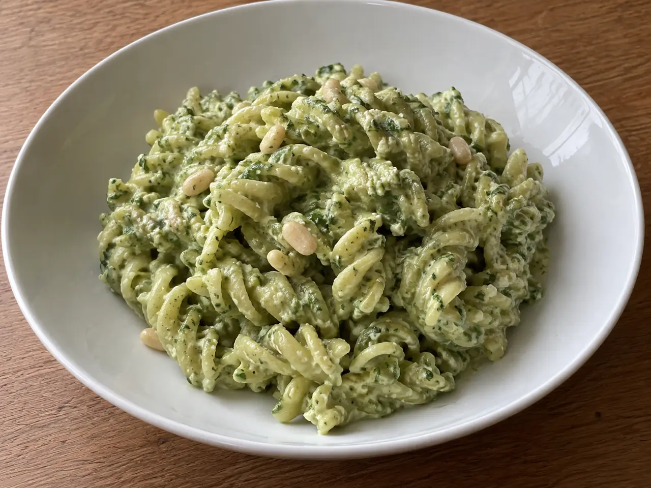 Pasta con pesto e ricotta cremosa con fusilli verdi, basilico fresco e salsa morbida nel piatto
