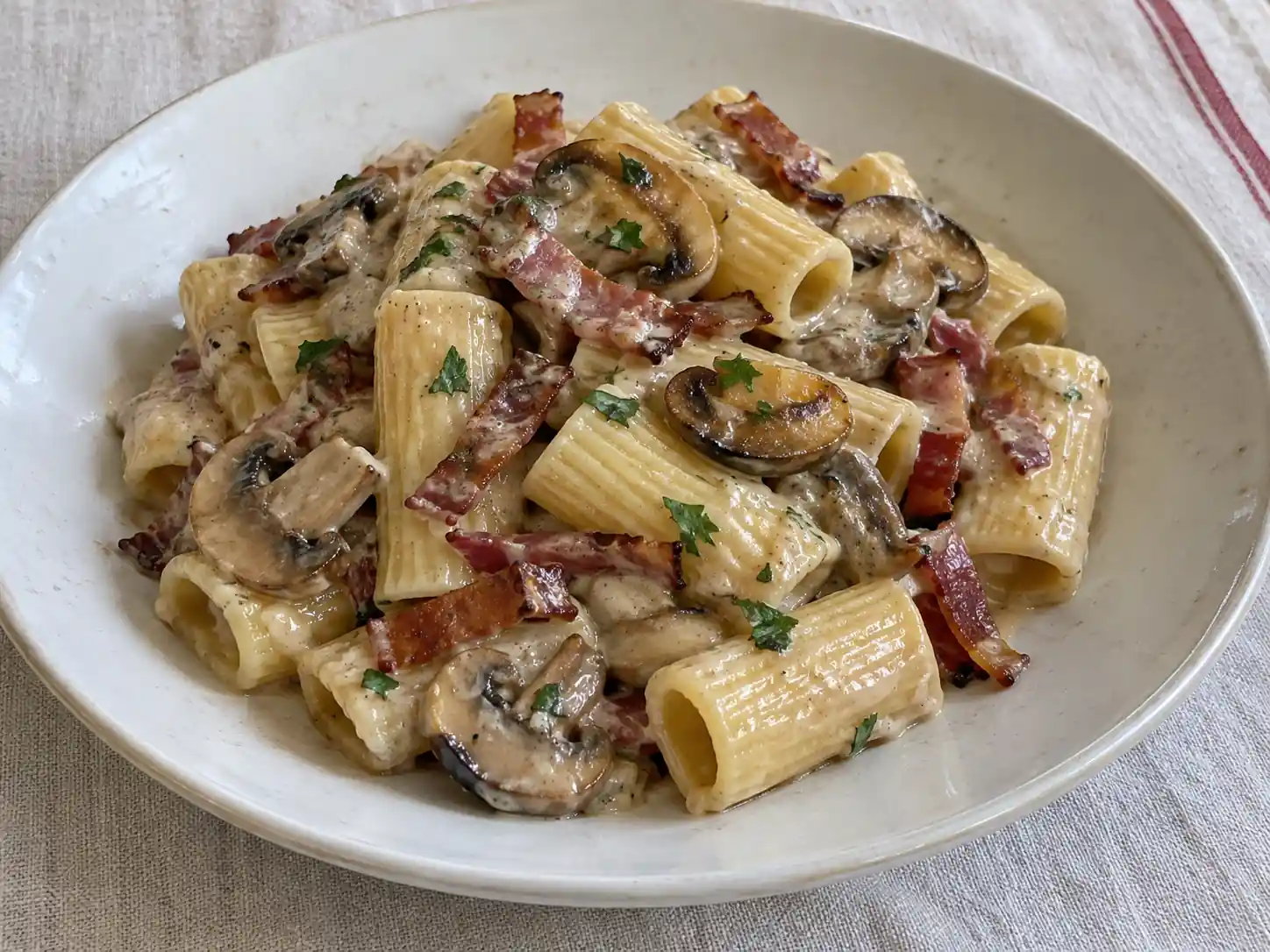 Pasta con speck e funghi cremosa con rigatoni, champignon dorati e listarelle di speck