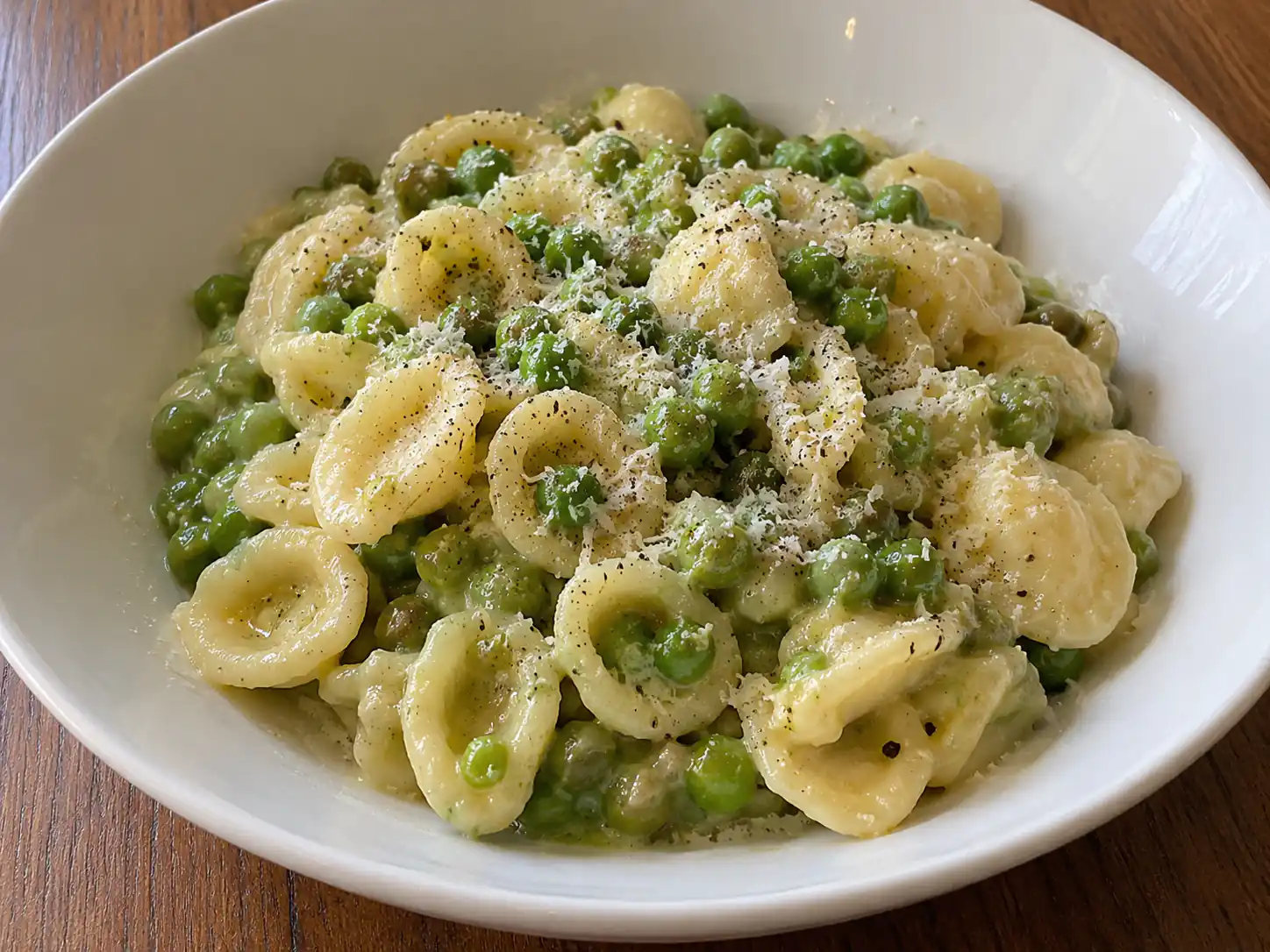 Pasta e piselli alla pugliese cremosa con orecchiette, piselli verdi e pecorino in piatto fondo
