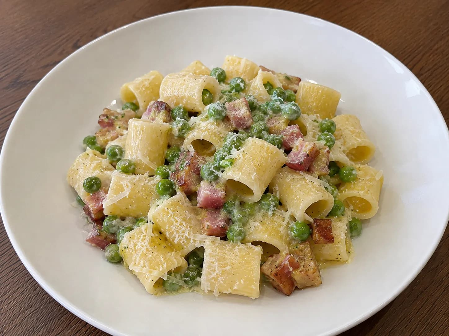 Pasta pancetta e piselli cremosa con mezze maniche, pancetta rosolata e piselli teneri