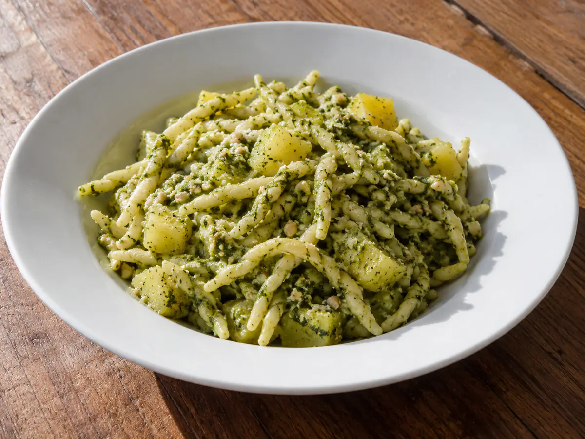 Pasta pesto e patate in piatto fondo con trofie verdi e cubetti di patata ben conditi