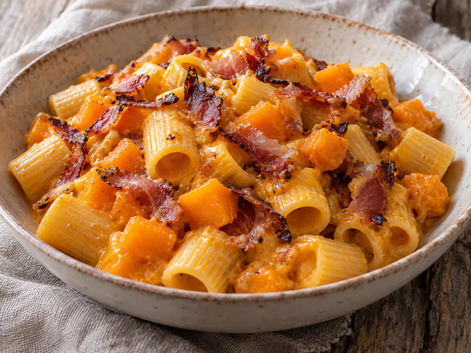 Mezze maniche con crema arancione di zucca e striscioline croccanti di speck in luce naturale