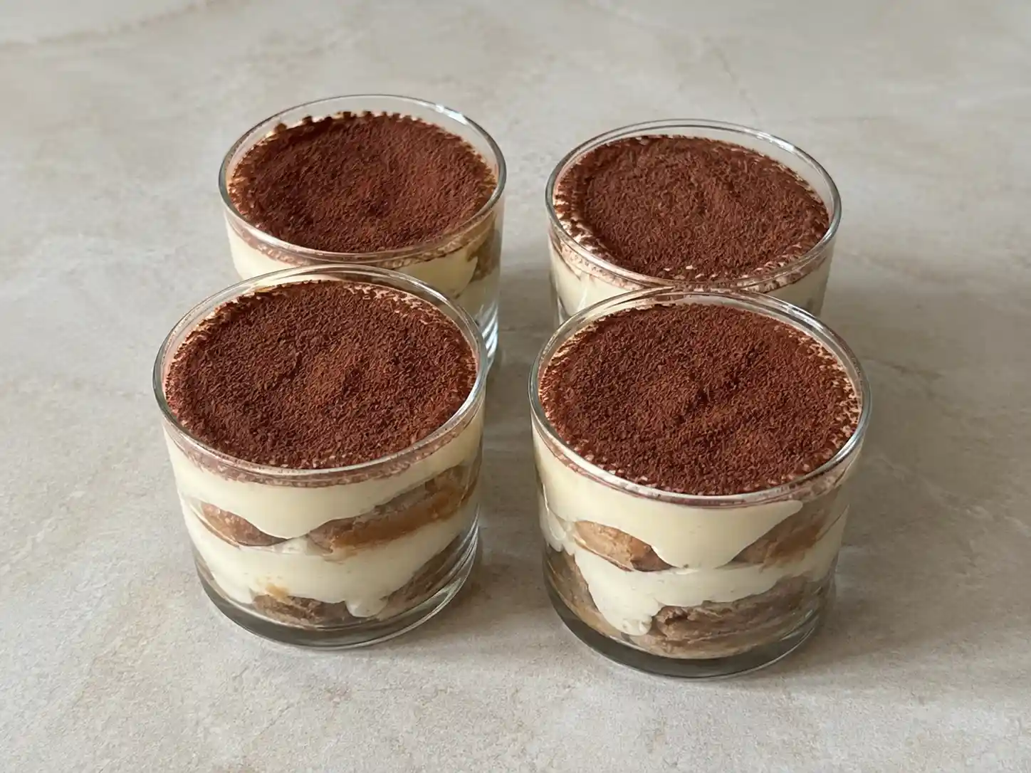 Tiramisù al bicchiere con strati di savoiardi al caffè, crema al mascarpone e cacao amaro
