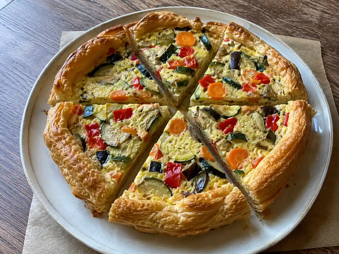 Torta salata alle verdure miste a fette con sfoglia dorata e ripieno di ricotta e ortaggi