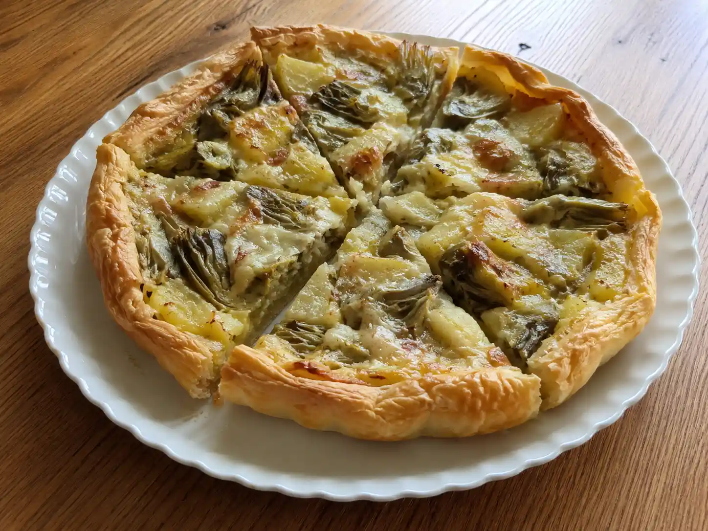 Torta salata carciofi e patate dorata, tagliata a fette con ripieno morbido di verdure e scamorza