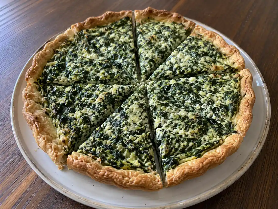 Torta salata cavolo nero con ricotta in fette dorate, ripieno verde e base brisée friabile