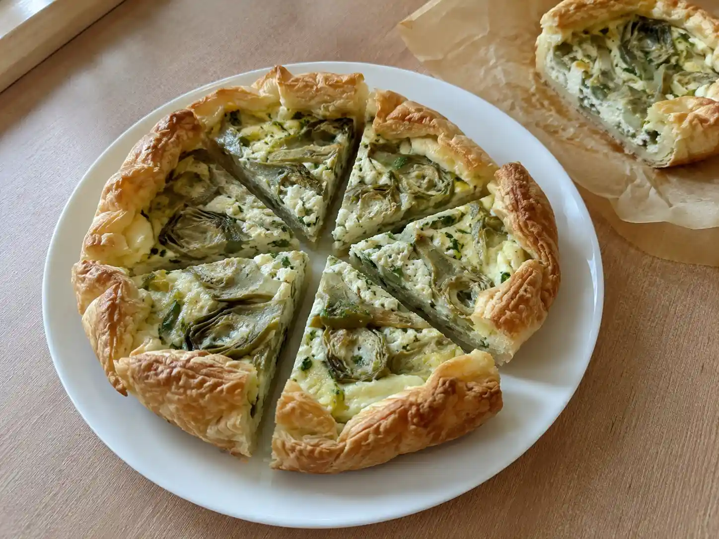 Torta salata con carciofi e ricotta a fette, con sfoglia dorata e ripieno cremoso visibile