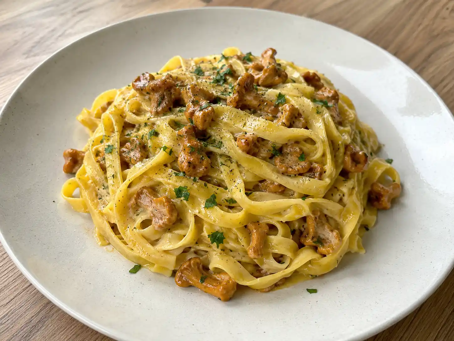 Finferli pasta con tagliatelle all'uovo, funghi dorati e prezzemolo su piatto chiaro
