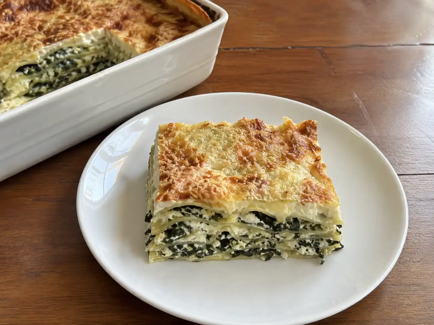 Lasagne ricotta e spinaci al forno con strati cremosi e superficie dorata in pirofila bianca