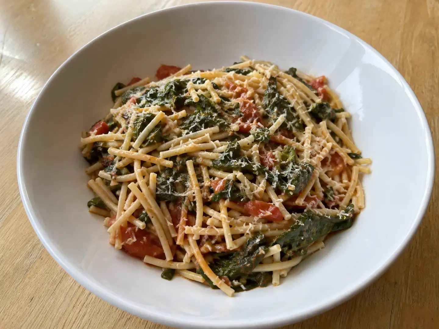 Pasta con i tenerumi asciutta con pomodoro fresco, foglie verdi e caciocavallo grattugiato