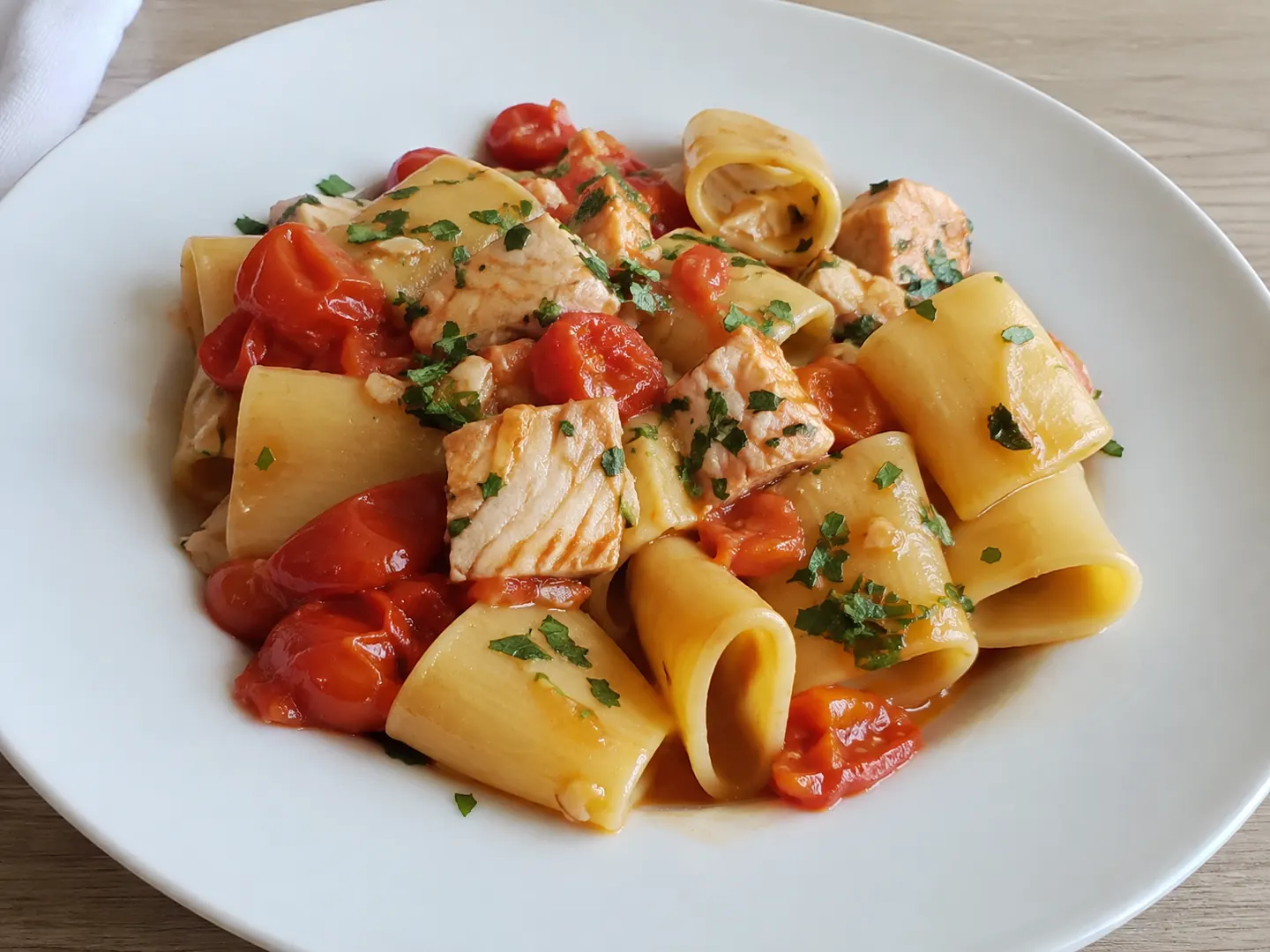 Pasta con la ricciola e pomodorini servita cremosa con pezzi di pesce e prezzemolo fresco