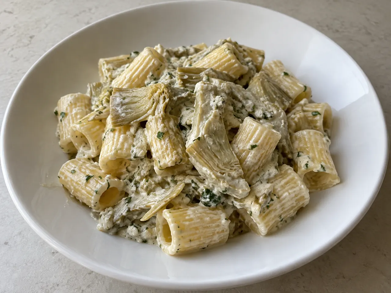 Pasta con ricotta e carciofi cremosa con mezze maniche, carciofi a spicchi e prezzemolo tritato