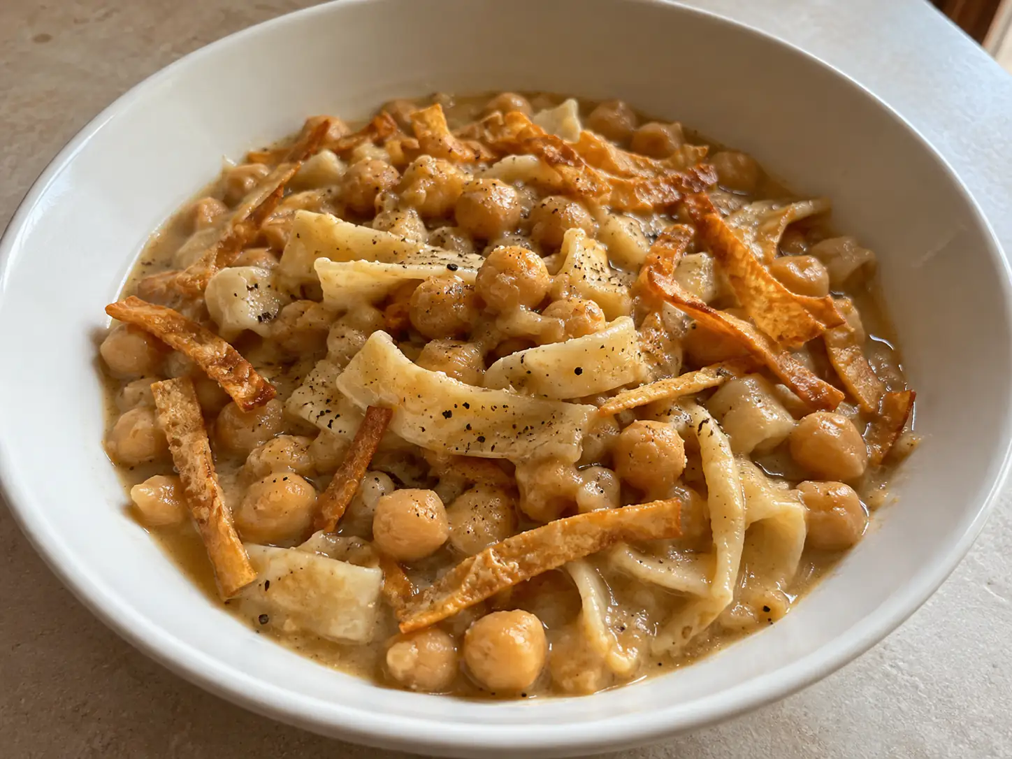 Pasta e ceci alla pugliese cremosa con tria dorata e ceci in piatto fondo bianco