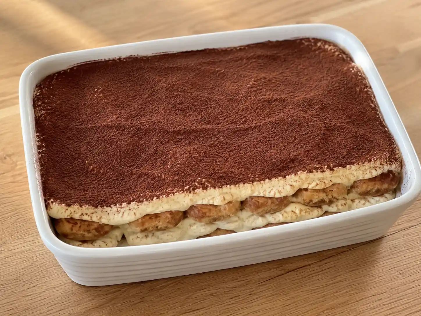 Tiramisù senza lattosio in pirofila, con savoiardi al caffè, crema chiara e cacao amaro