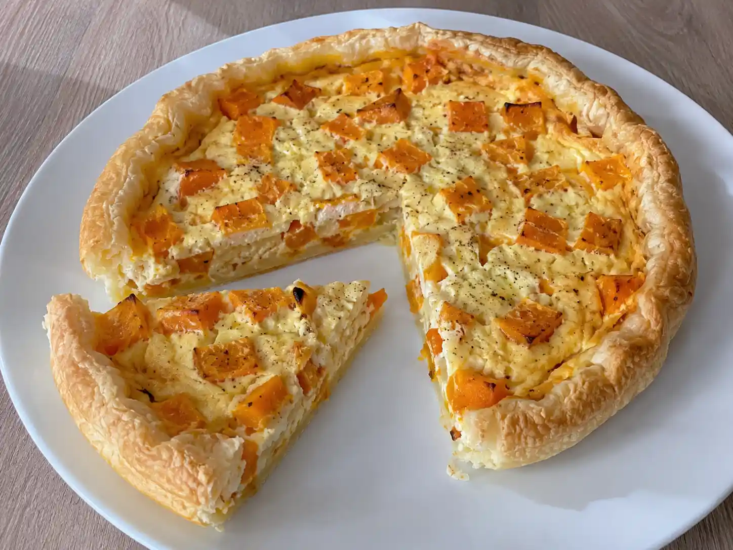 Torta salata zucca e ricotta a fette, dorata e cremosa, con guscio di pasta sfoglia